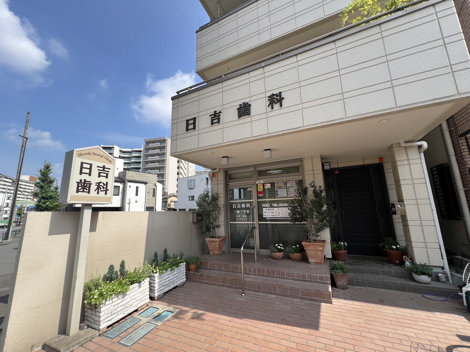 青空の下の日吉歯科の外観と入口